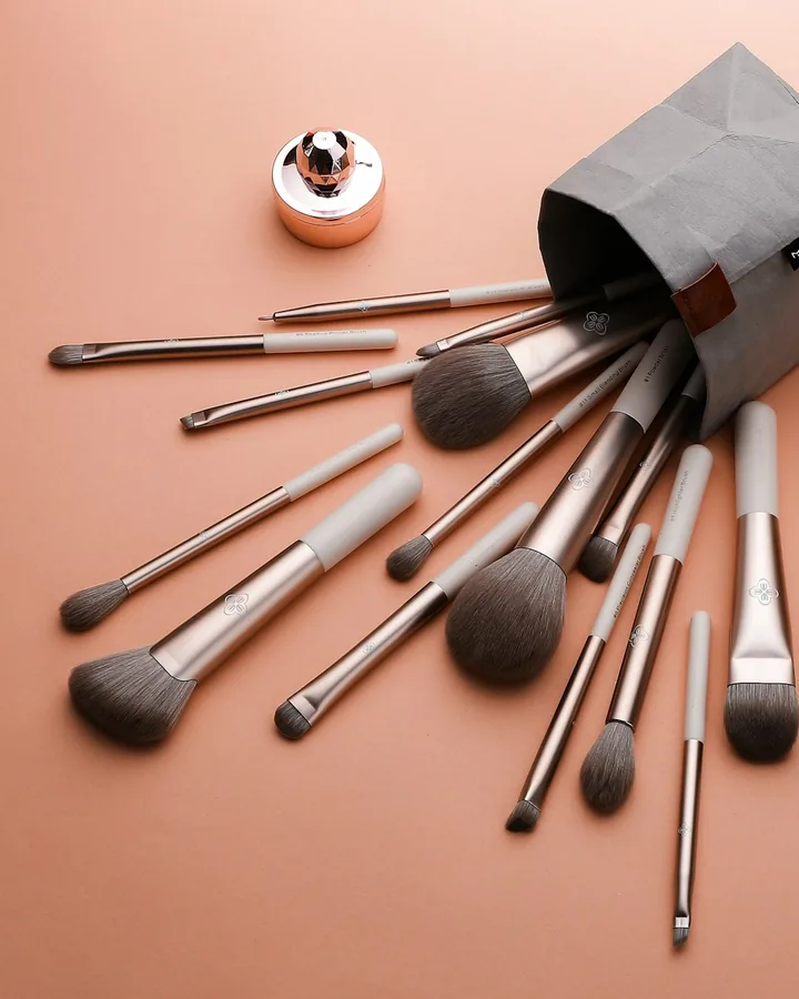 Pinceaux de maquillage et roses sur un fond rose