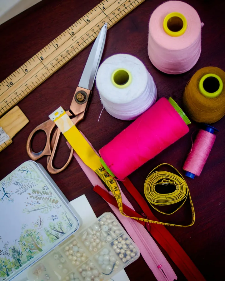 Bobines de fil, ciseaux et ruban à mesurer sur une table de couture