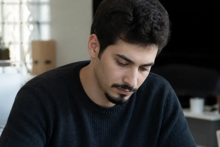 Homme pensif avec un pull noir et un bouc dans un intérieur moderne