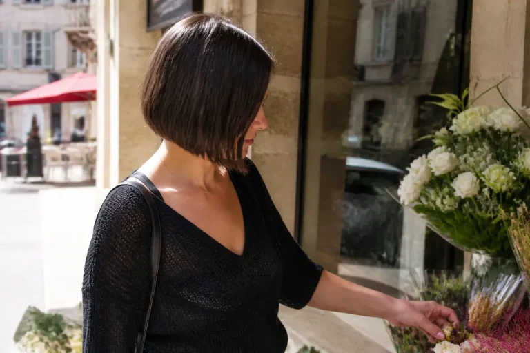 Femme à la coiffure en carré plongeant examinant des fleurs en extérieur