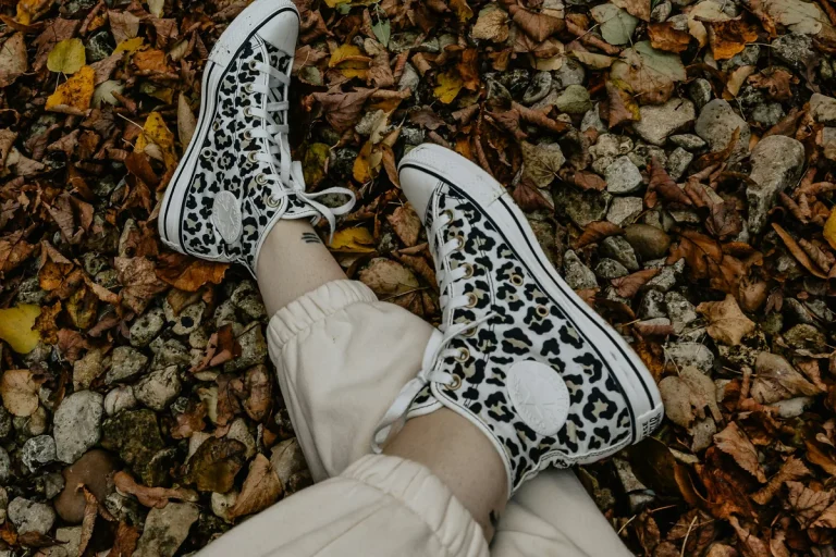 Baskets montantes à motif léopard portées sur un tapis de feuilles mortes