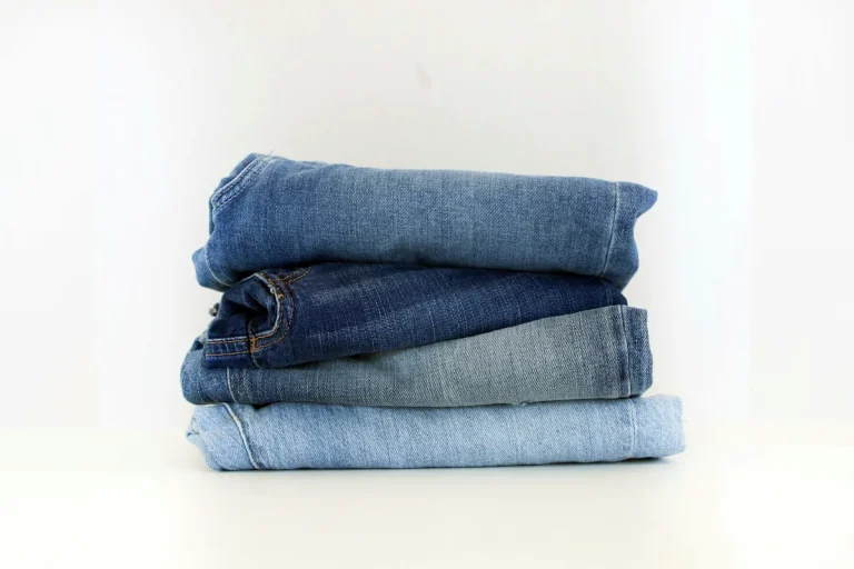 Pile de jeans de différents bleus sur fond blanc